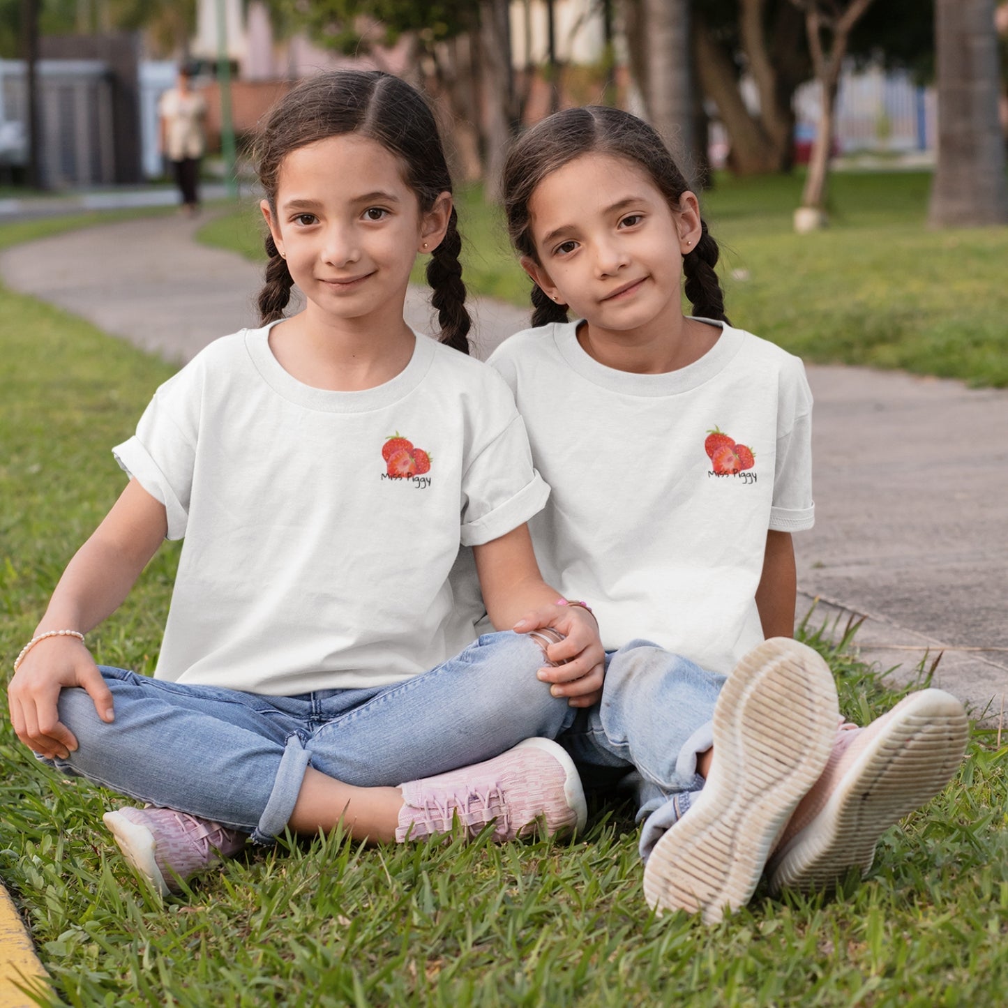 Two kids wearing the JUICY t-shirt in white. Unisex organic cotton design with soft texture and playful energy, shown in a light and joyful setting.