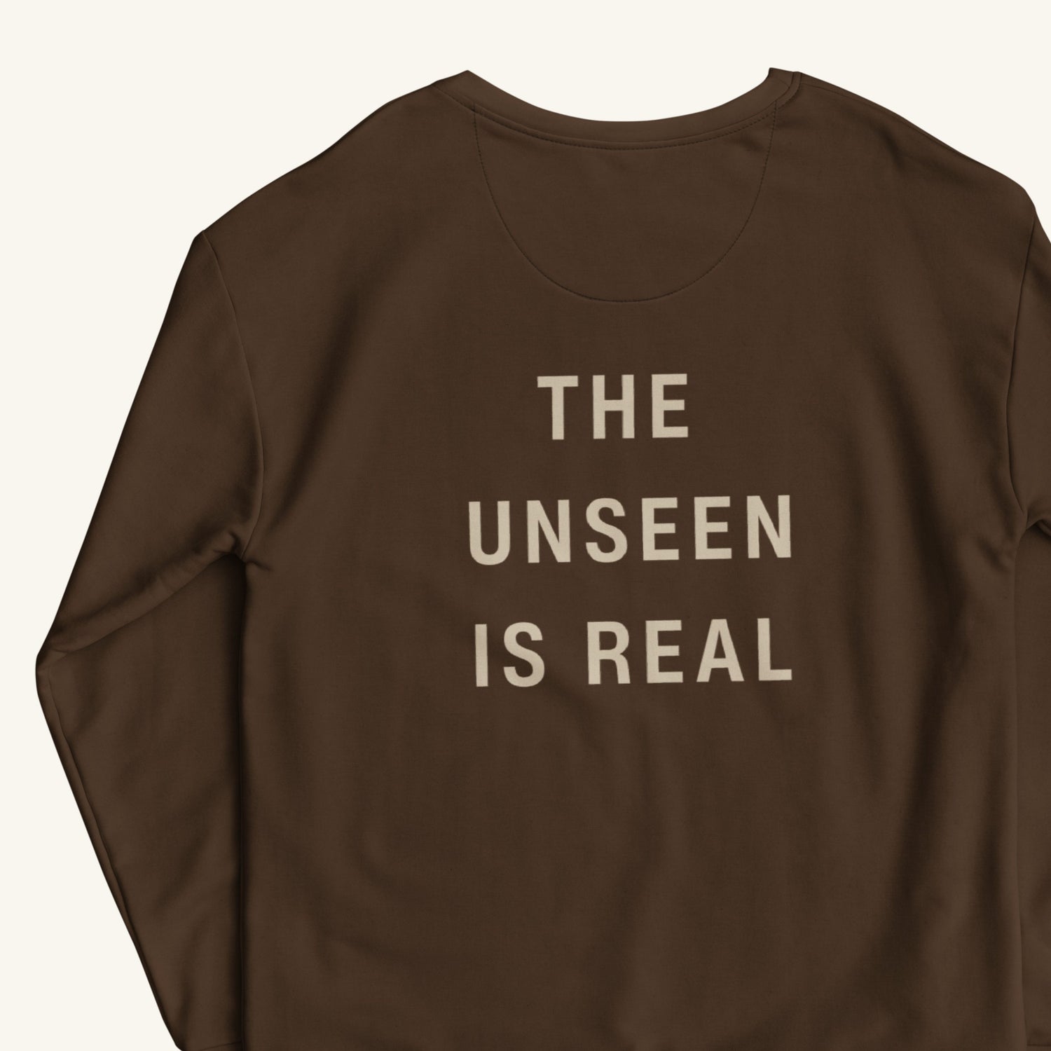 Brown sweatshirt with 'THE UNSEEN IS REAL' text on a white background