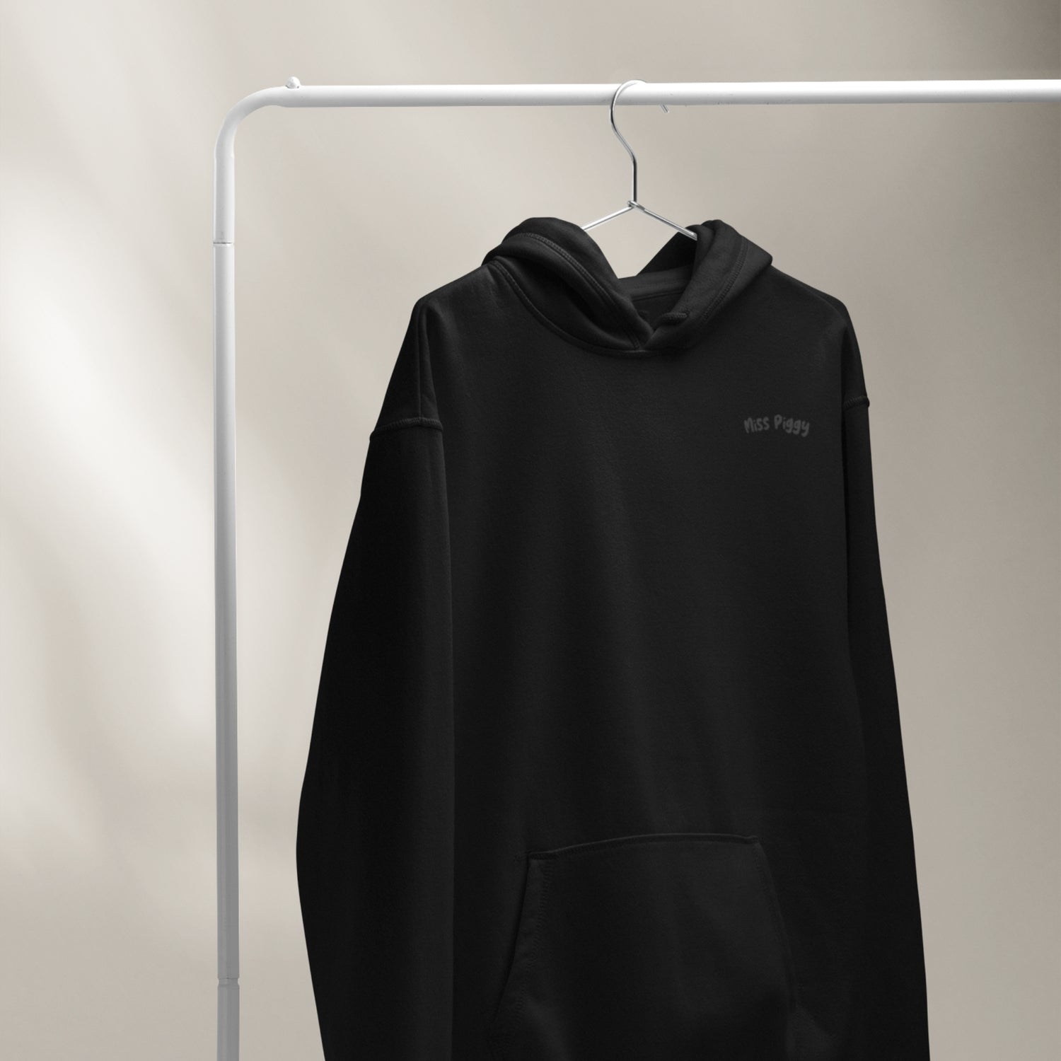 Black hoodie with a brand logo on a hanger against a neutral background