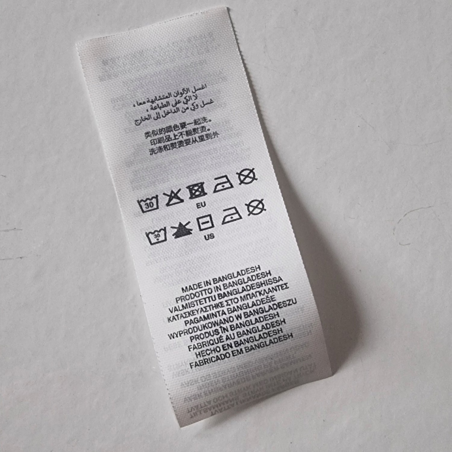 Textile label with care instructions and product details on a gray background