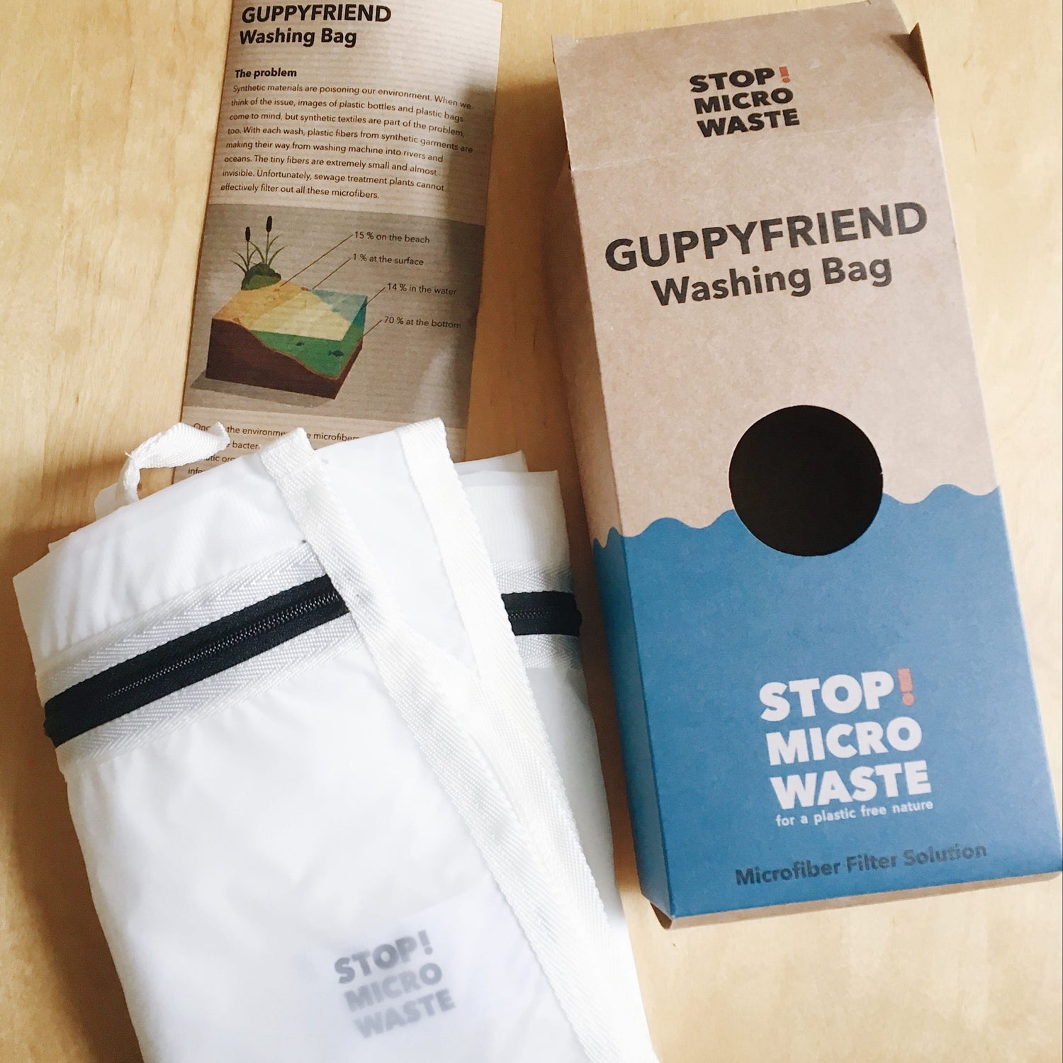 Guppyfriend washing bag and packaging on a wooden surface