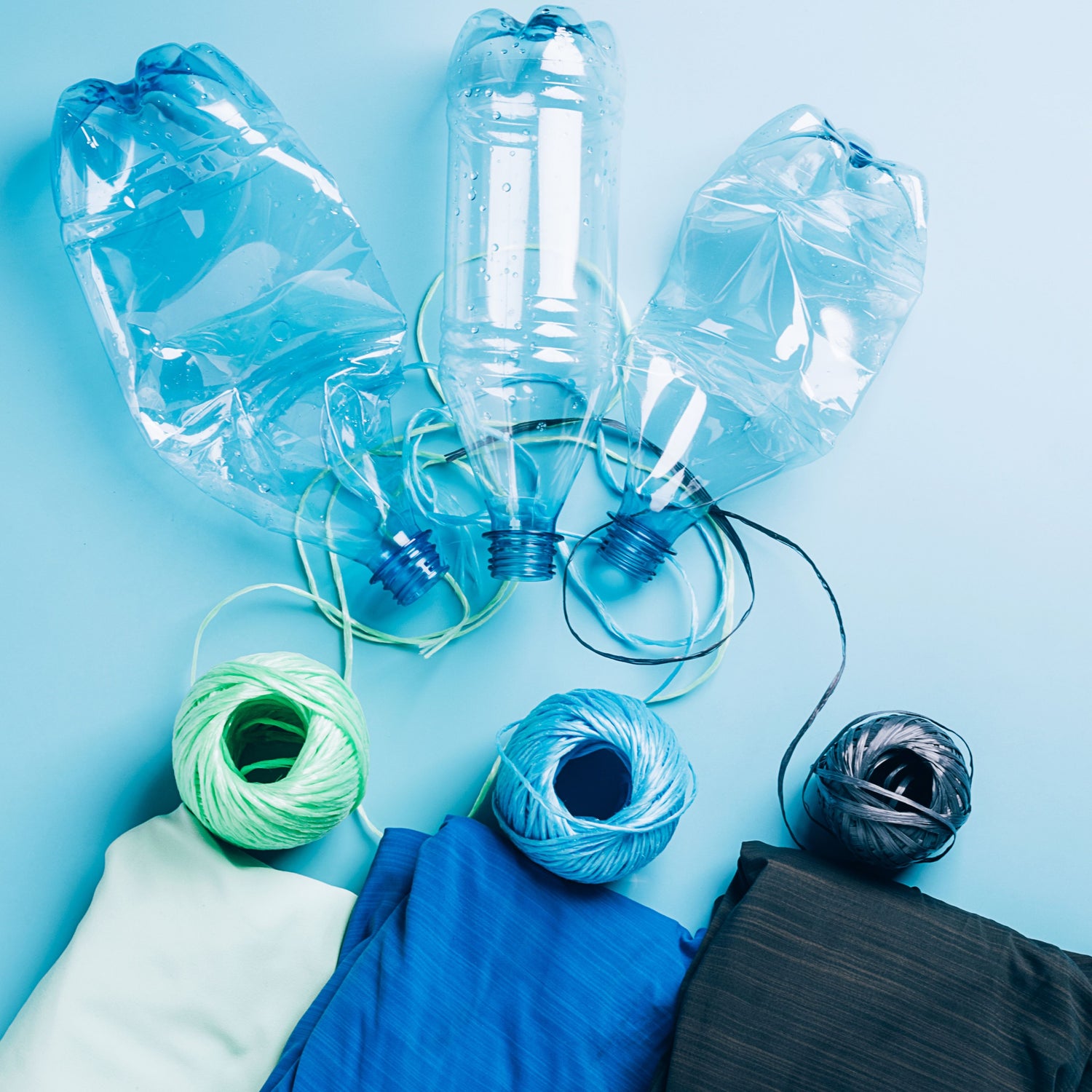 Recycled plastic bottles, yarn, and fabric on a blue background