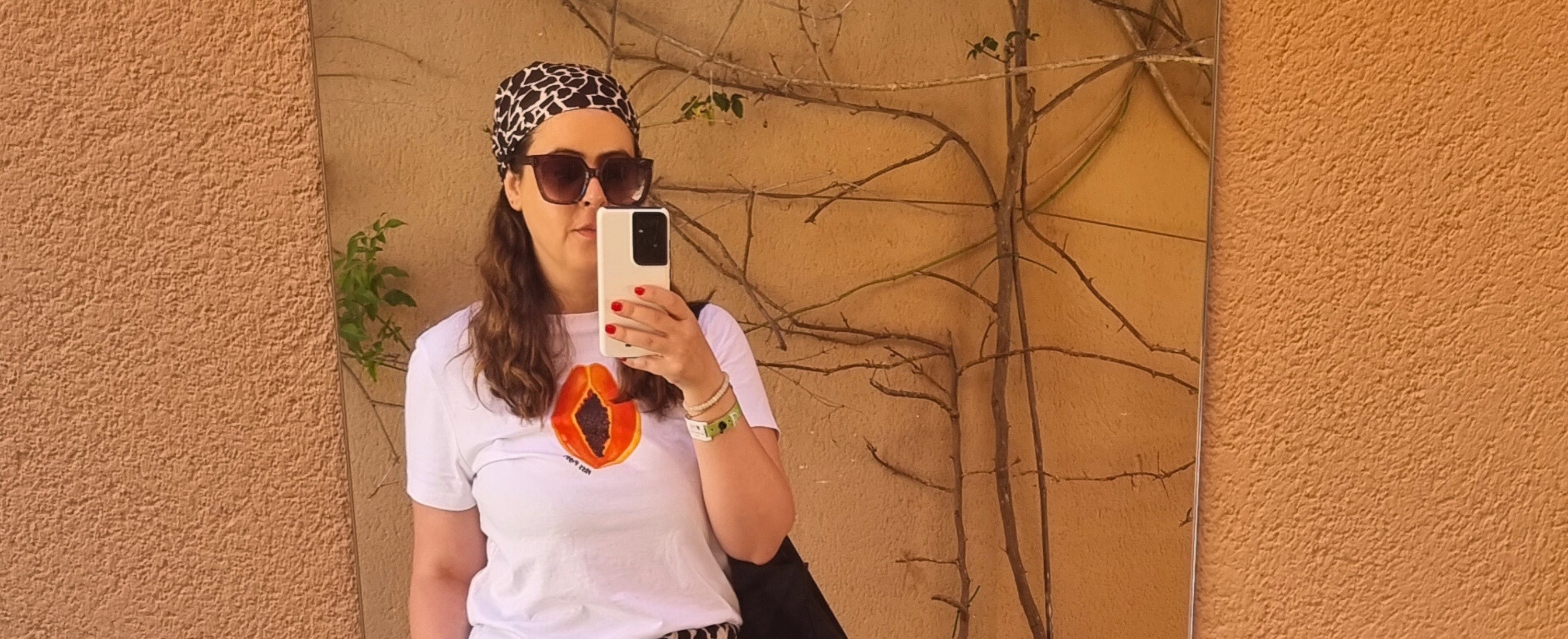 Miss Piggy founder taking a mirror selfie wearing sunglasses and PAPAYA organic t-shirt with UNSEEN recycled bandana.