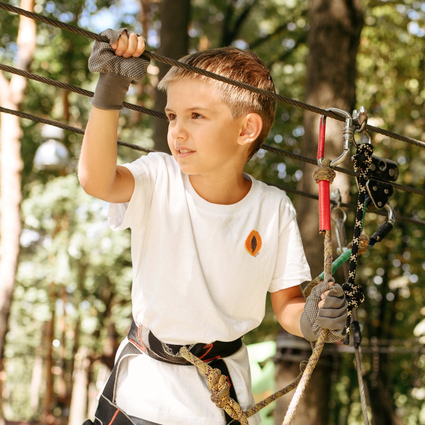 Child wearing the PAPAYA t-shirt in white. Unisex organic cotton design with soft texture and playful energy, shown in a light and joyful setting.