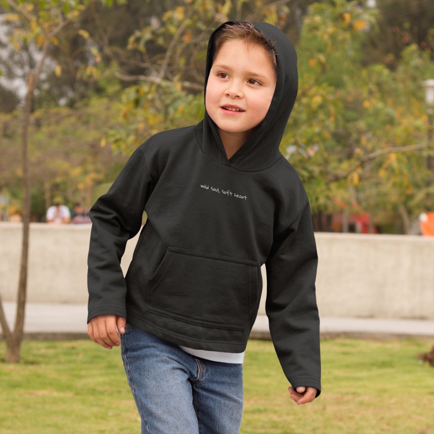Child wearing the SOUL SNUG hoodie in a relaxed fit, made from organic cotton and recycled polyester. Unisex design with soft texture and natural tone, photographed against a light, playful background