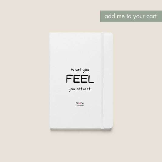 Notebook with 'What you FEEL, you attract' text on a textured surface with photos and earphones.
