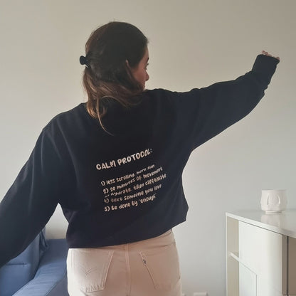 Unisex PROTOCOL Organic Sweater in black with white print, minimalist sustainable design by Miss Piggy.