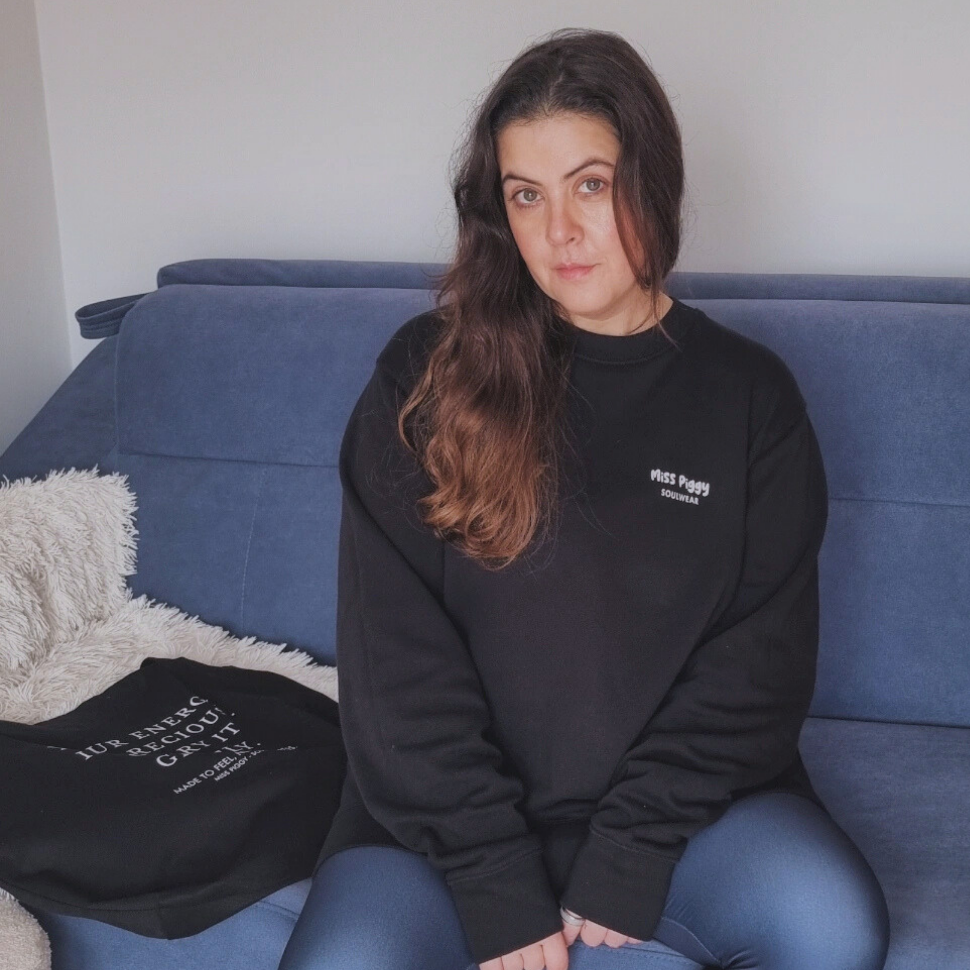 Founder wearing Protocol organic sweater black sitting on a blue couch.