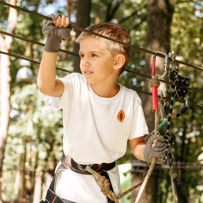 Child wearing the PAPAYA t-shirt in white. Unisex organic cotton design with soft texture and playful energy, shown in a light and joyful setting.